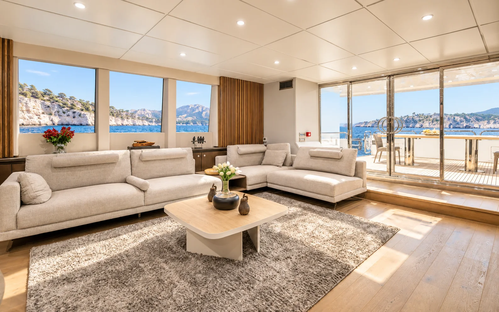 The saloon on the main deck: a long run of windows, light oak floor, pale sofas and white cabinetry